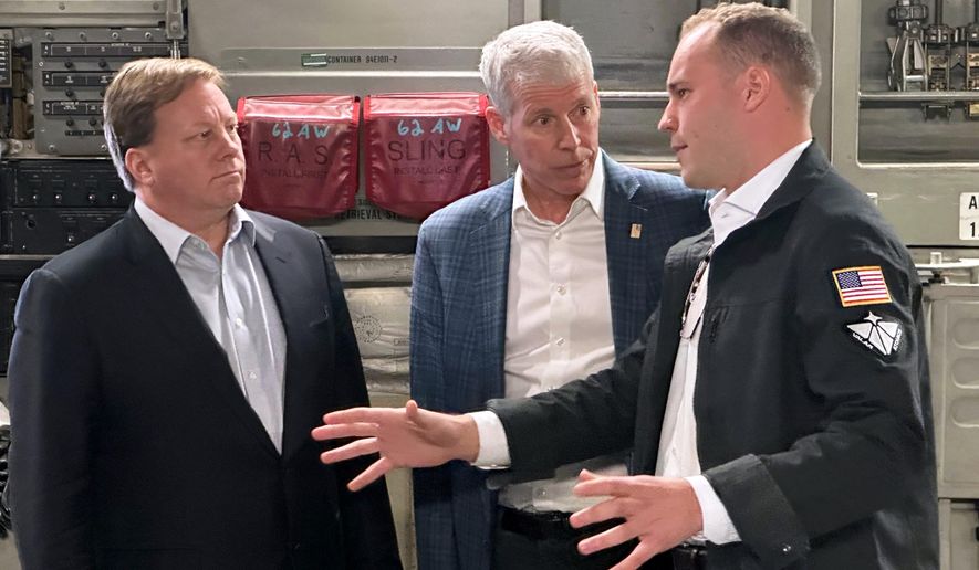 Energy Secretary Chris Wright, center, and Under Secretary of Defense Michael Duffey, left, listen as Isaiah Taylor, CEO of Valar Atomics, discusses a microreactor developed by Valar to generate nuclear power for the military and commercial customers, Sunday, Feb. 15, 2026, in-flight, on board a C-17. (AP Photo/Matthew Daly)