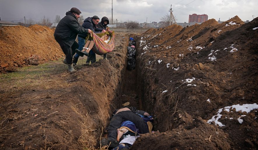 Bodies are placed into a mass grave on the outskirts of Mariupol, Ukraine, Wednesday, March 9, 2022. (AP Photo/Evgeniy Maloletka, File)