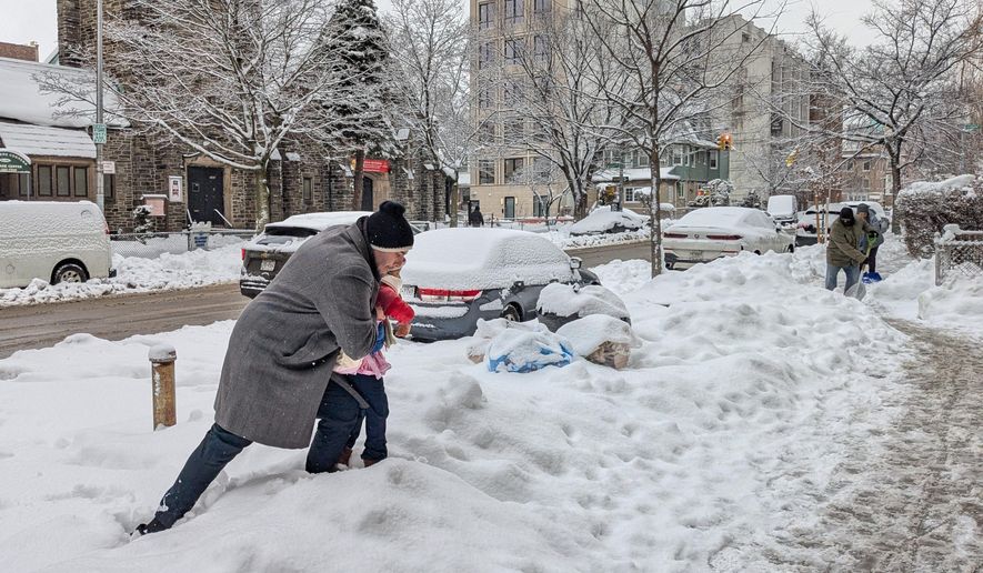 A man carries his daughter over a snowbank outside a day care center in the Brooklyn borough of New York, on Wednesday, Feb. 25, 2026. (AP Photo/Drew Callister)