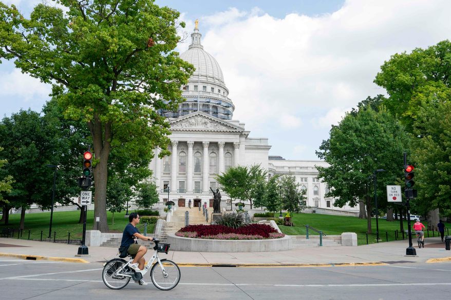 FILE - A cyclist rides past the Wisconsin State Capitol July 30, 2024, in Madison, Wis. (AP Photo/Kayla Wolf, File)