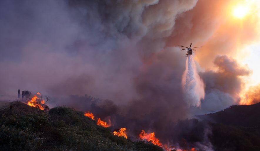 Water is dropped by helicopter on the advancing Palisades Fire in the Pacific Palisades neighborhood of Los Angeles, Tuesday, Jan. 7, 2025. (AP Photo/Etienne Laurent, File)