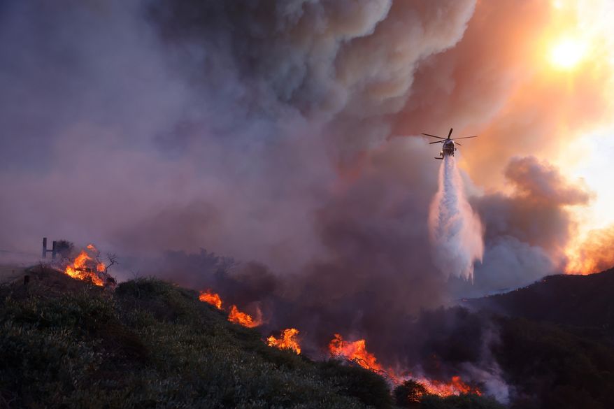 Water is dropped by helicopter on the advancing Palisades Fire in the Pacific Palisades neighborhood of Los Angeles, Tuesday, Jan. 7, 2025. (AP Photo/Etienne Laurent, File)