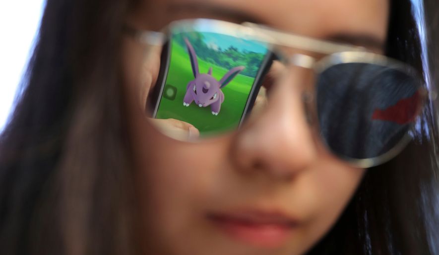 A mobile screen is reflected on a fan's sunglasses as she plays "Pokemon Go" in Hong Kong, on July 25, 2016. (AP Photo/Kin Cheung, File)