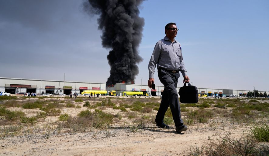 A man walks away after watching as a black plume of smoke rises from a warehouse in the industrial area of Sharjah City, United Arab Emirates, Sunday, March 1, 2026, following reports of Iranian strikes in Dubai. (AP Photo/Altaf Qadri)