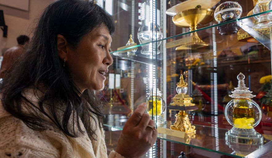 Buddhist practitioner and disciple of Master YongHua, Sarah Kim, shows the Fragrant Oil Shariras among other Buddhist relics displayed at Wei Mountain Temple, in Rosemead, Calif., Saturday, Feb. 17, 2024. (AP Photo/Damian Dovarganes)