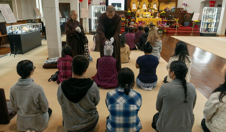 Buddhist resident monks perform a blessing to devotees and visitors at Wei Mountain Temple, in Rosemead, Calif., Saturday, Feb. 17, 2024. (AP Photo/Damian Dovarganes)