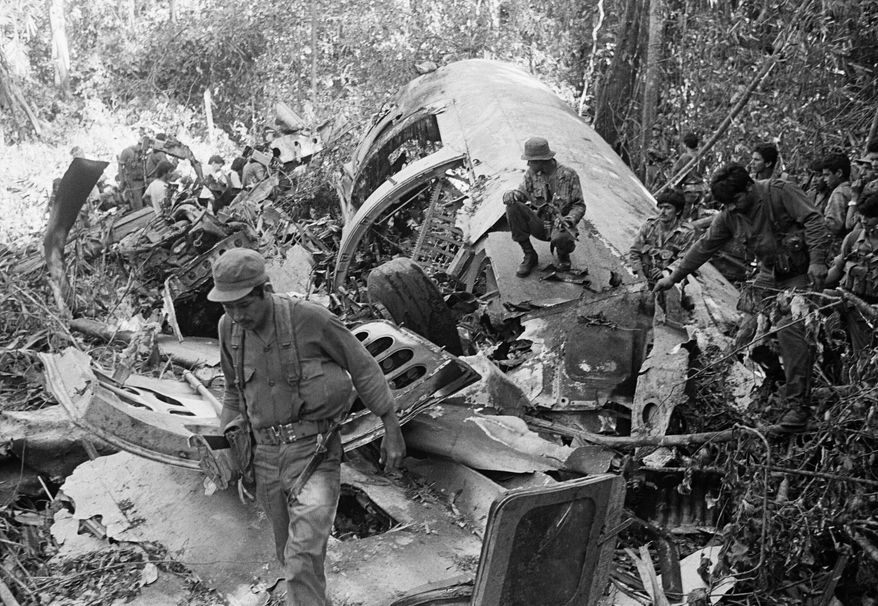 FILE - Sandinista soldiers walk amid the debris after shooting down a supply plane of the U.S.-backed rebels in Loma El Arenal, Nicaragua, on Jan. 24, 1988. (AP Photo/Mario Tapia, File)