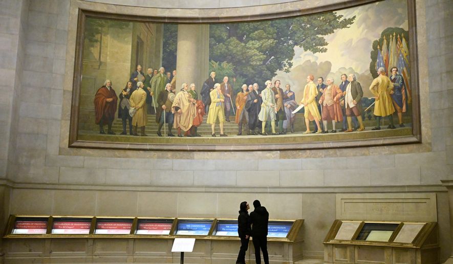 Two visitors look at exhibits beneath a large wall mural showing the signing of the Declaration of Independence at the National Archives Thursday, Jan. 29, 2026, in Washington. (AP Photo/John McDonnell)
