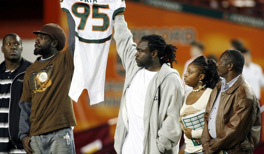 FILE - Bryan Pata's family holds up his jersey at the beginning of an NCAA college football game between Miami and Boston College, Nov. 23, 2006, in Miami. (AP Photo/Luis M. Alvarez, File)