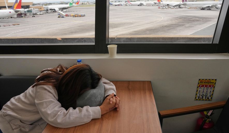 An overseas Filipino worker sleeps as she waits for updates on her cancelled flight to the Middle East at Manila's International Airport, Philippines on Monday, March 2, 2026. (AP Photo/Aaron Favila)