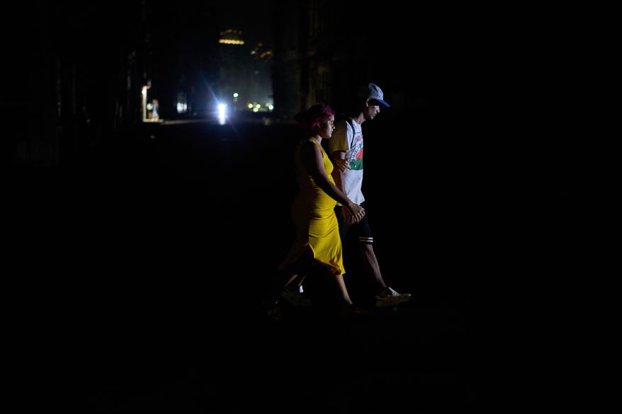 People cross a street during a blackout in Havana, Wednesday, March 4, 2026. (AP Photo/Ramon Espinosa)