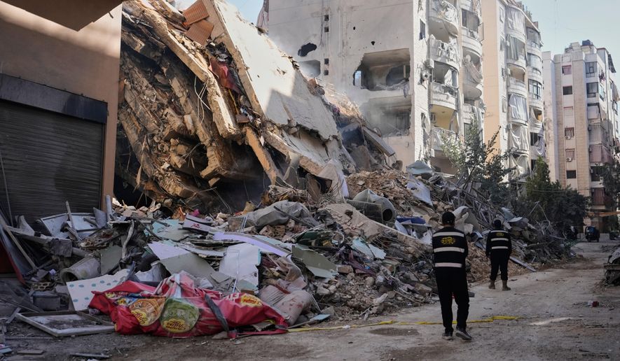 Hezbollah members walk past a building destroyed by an Israeli airstrike in Dahiyeh, Beirut's southern suburbs, Lebanon, Thursday, March 5, 2026. (AP Photo/Hassan Ammar) ** FILE **