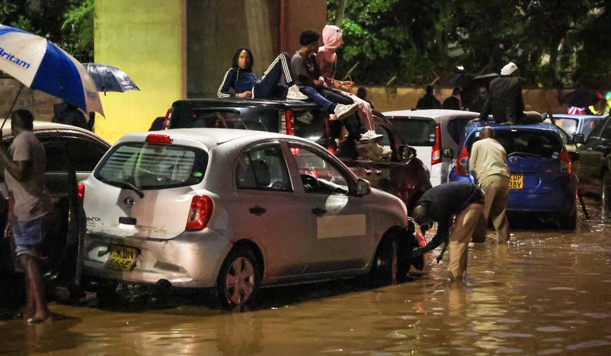 People climb on top of their cars after heavy rains flooded roads in Nairobi, Kenya, on Friday, March 6, 2026. (AP Photo/Andrew Kasuku)