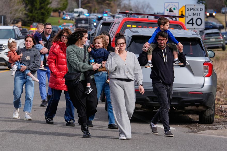 Law enforcement escort families with children away from the Temple Israel synagogue Thursday, March 12, 2026, in West Bloomfield Township, Mich. (AP Photo/Paul Sancya)