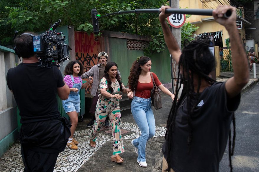 Actors Alana Cabral, behind left, Dira Paes, center, Sophie Charlotte, behind right, and Paulo Mendes, behind everyone, take part in the filming of the soap opera "Três Garças" at a TV Globo set in Rio de Janeiro, Thursday, March 12, 2026. (AP Photo/Bruna Prado)