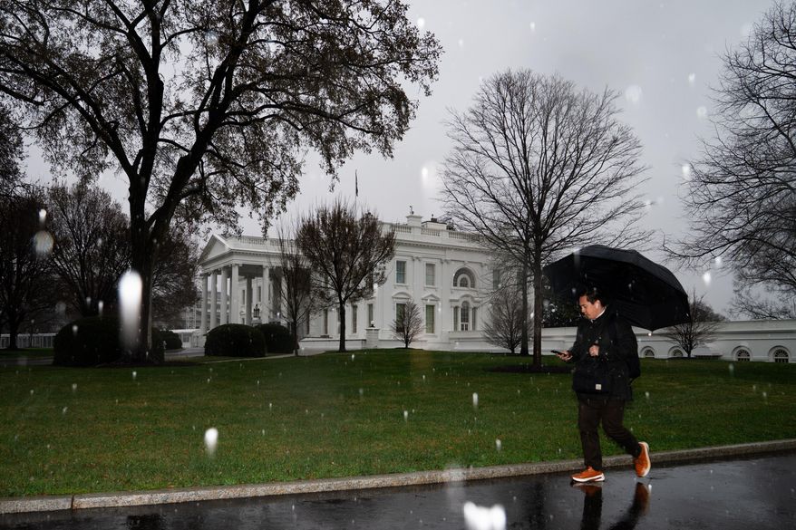 A person walks through falling snow at the White House on Thursday, March 12, 2026, in Washington. (AP Photo/Allison Robbert)