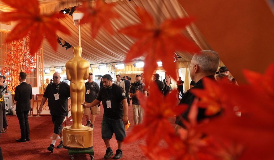 Workers install an Oscar statue Saturday, March 14, 2026, at the Dolby Theatre in Los Angeles, in preparation for Sunday's 98th Academy Awards ceremony. (AP Photo/Gregory Bull)