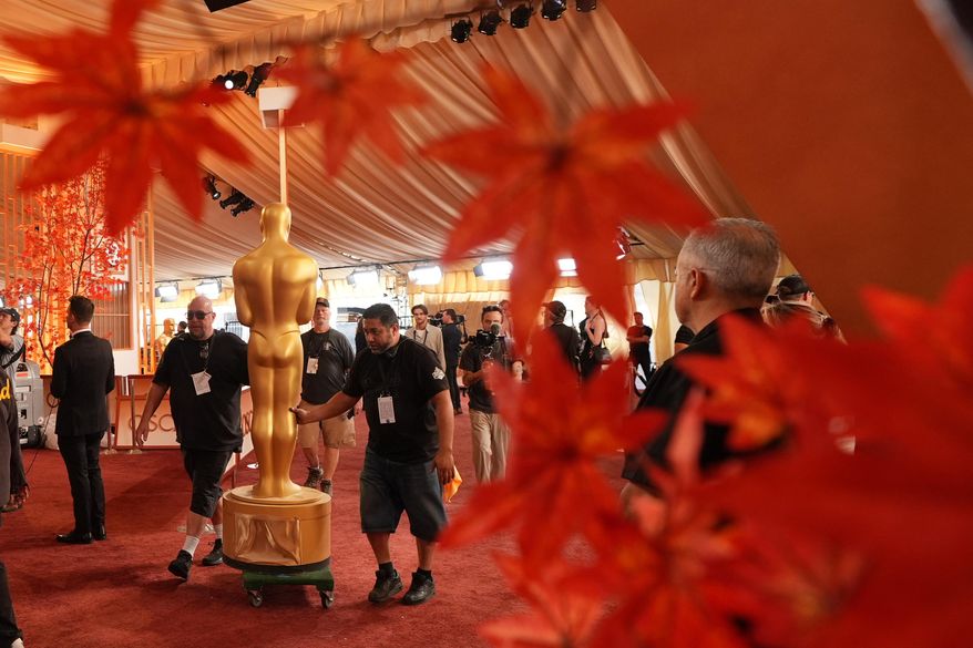 Workers install an Oscar statue Saturday, March 14, 2026, at the Dolby Theatre in Los Angeles, in preparation for Sunday's 98th Academy Awards ceremony. (AP Photo/Gregory Bull)