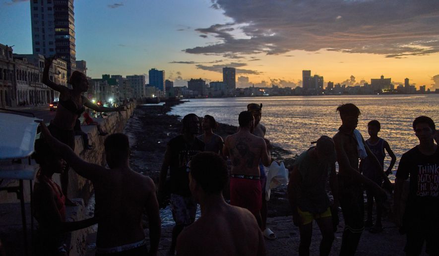 People watch the sunset from the Malecón during a blackout in Havana, Monday, March 16, 2026. (AP Photo/Ramon Espinosa)