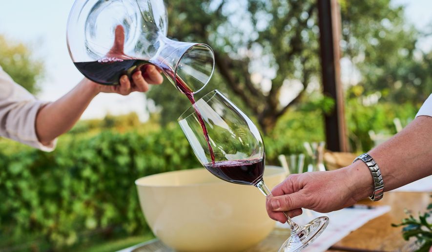 A worker serves red wine to tourists during a tasting at the Lagarde Winery in Mendoza, Argentina, Thursday, March 12, 2026. (AP Photo/Rodrigo Abd)