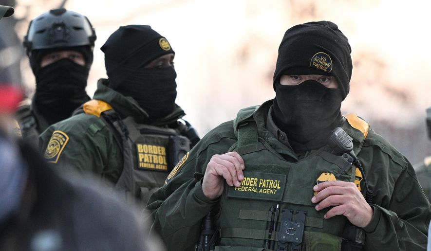 Federal agents look on as protesters gather outside the Bishop Henry Whipple Federal Building, Thursday, Jan. 8, 2026, in Minneapolis, Minn. (AP Photo/Tom Baker, File)