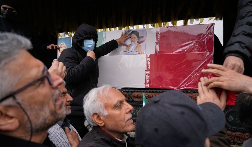 Iranians reach toward the coffins as they follow the funeral procession of Iran's intelligence minister Esmail Khatib and, according to Iranian officials, his wife and daughter, in Tehran, Iran, Friday, March 20, 2026. (AP Photo/Vahid Salemi)