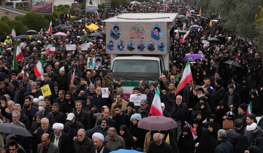 Iranians follow a truck carrying the coffins of Iran's intelligence minister Esmail Khatib and, according to Iranian officials, his wife and daughter, during a funeral procession in Tehran, Iran, Friday, March 20, 2026. (AP Photo/Vahid Salemi)