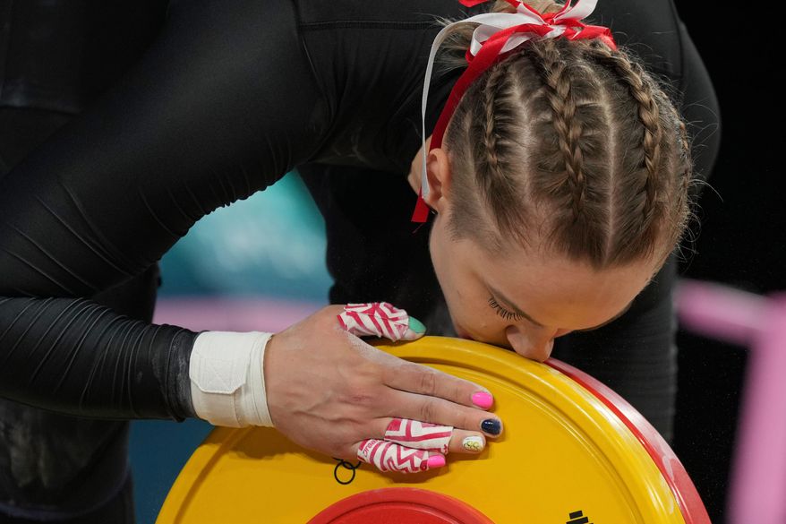 Weronika Zielinska of Poland kisses the weight as she competes during the women's 81kg weightlifting event, at the 2024 Summer Olympics, Saturday, Aug. 10, 2024, in Paris, France. (AP Photo/Kin Cheung,File)
