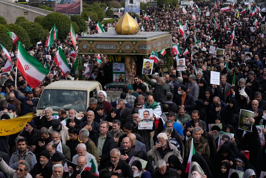 People follow a truck carrying the flag draped coffins of Gen. Ali Mohammad Naeini, a spokesperson for Iran’s paramilitary Revolutionary Guard and one of his comrades Amir Hossein Bidi during their funeral procession in Tehran, Iran, Saturday, March 21, 2026. (AP Photo/Vahid Salemi)