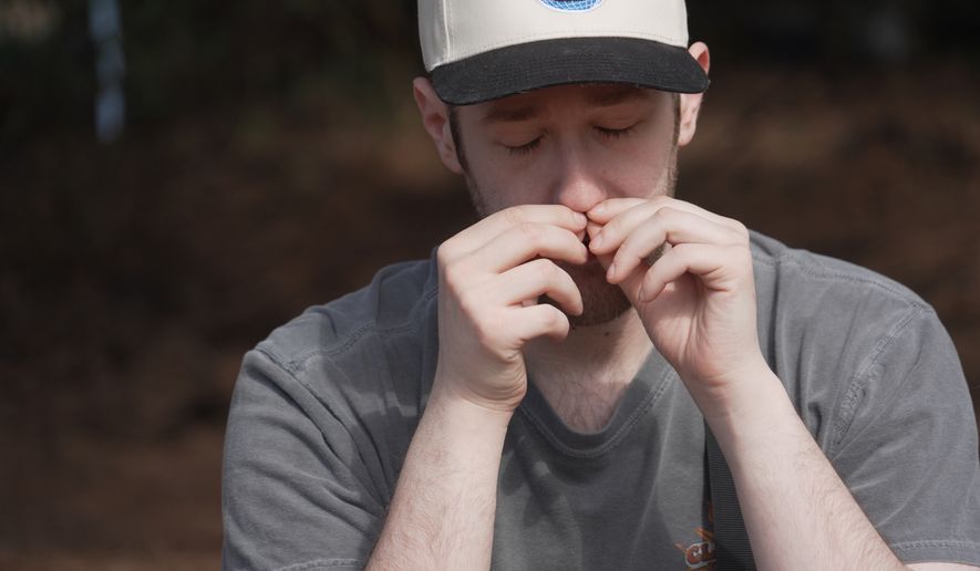 Alan Mintz smells a crushed conifer twig during a "forest bathing" session at the J.C. Raulston Arboretum in Raleigh, N.C., on Sunday, March 22, 2026. (AP Photo/Allen G. Breed)