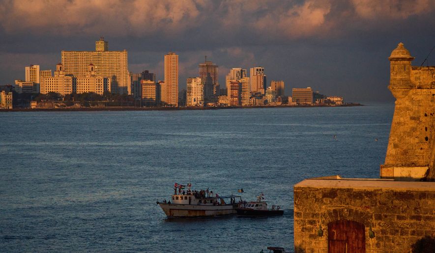 Activists wave Cuban and Palestinian flags from the vessel Maguro, arriving from Mexico with humanitarian aid as part of the "Nuestra America," or Our America Convoy, in Havana Bay, Cuba, Tuesday, March 24, 2026. (AP Photo/Ramon Espinosa)