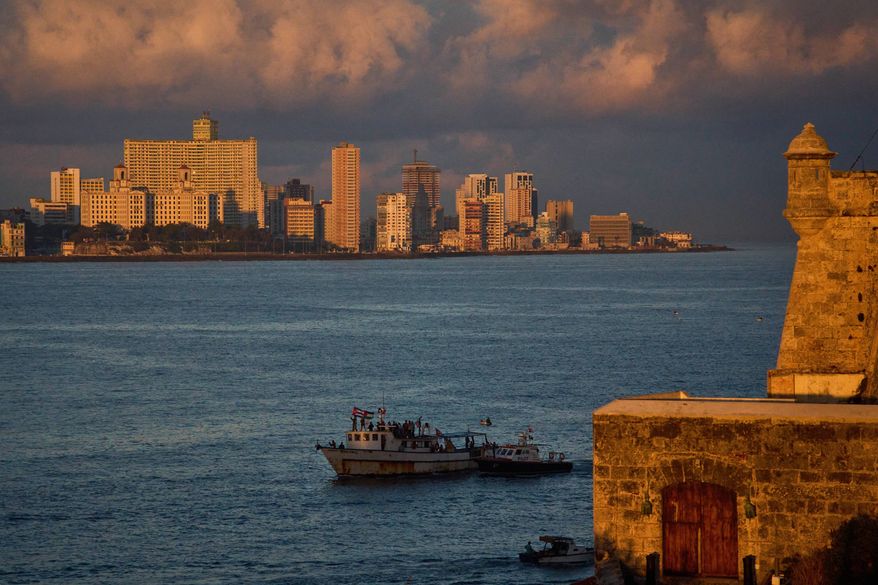 Activists wave Cuban and Palestinian flags from the vessel Maguro, arriving from Mexico with humanitarian aid as part of the "Nuestra America," or Our America Convoy, in Havana Bay, Cuba, Tuesday, March 24, 2026. (AP Photo/Ramon Espinosa)