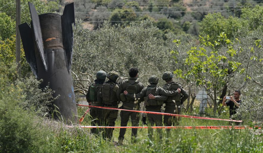Israeli soldiers take their photo beside the wreckage of an Iranian missile that landed in the West Bank village of Kifl Haris Tuesday, March 24, 2026. (AP Photo/Majdi Mohammed)