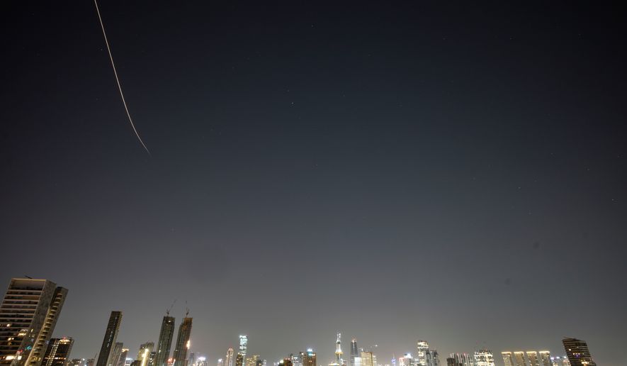 Missiles launched from Iran streak across the sky over central Israel, early Tuesday, March 24, 2026. (AP Photo/Ohad Zwigenberg)