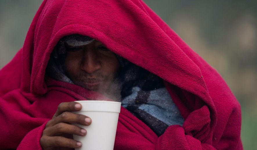 FILE - A migrant from Venezuela drinks a hot coffee amid cold weather at a makeshift camp along the Rio Grande riverbank on the U.S.-Mexico Border in Matamoros, Mexico, Dec. 23, 2022. (AP Photo/Fernando Llano, file)