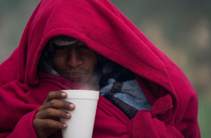 FILE - A migrant from Venezuela drinks a hot coffee amid cold weather at a makeshift camp along the Rio Grande riverbank on the U.S.-Mexico Border in Matamoros, Mexico, Dec. 23, 2022. (AP Photo/Fernando Llano, file)