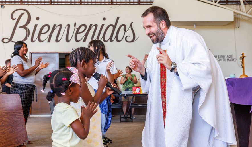The Rev. Brian Strassburger smiles as Alcala Bouilly sings into the microphone during Mass at Casa del Migrante on Thursday, March 19, 2026, in Reynosa, Mexico. (AP Photo/Michael Gonzalez)