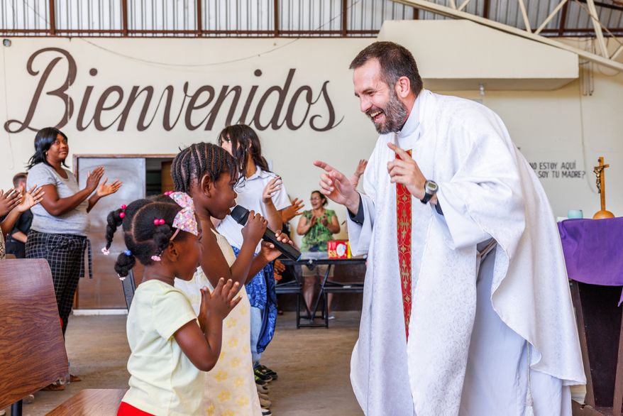 The Rev. Brian Strassburger smiles as Alcala Bouilly sings into the microphone during Mass at Casa del Migrante on Thursday, March 19, 2026, in Reynosa, Mexico. (AP Photo/Michael Gonzalez)