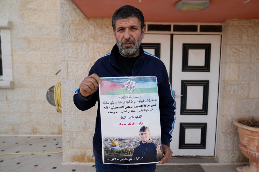 FILE - Khalid Ahmad holds a poster of his 17-year-old son, Walid Ahmad, who died in an Israeli prison, that reads in Arabic, "The hero prisoner Martyr, mercy and eternity for our righteous Martyrs," in the West Bank town of Silwad, northeast of Ramallah, March 26, 2025. (AP Photo/Nasser Nasser, File)
