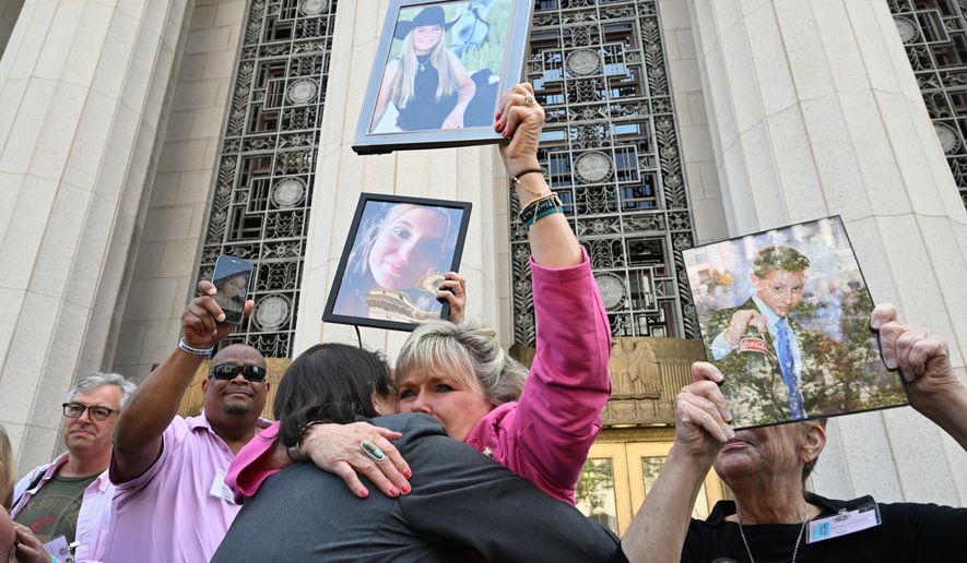 Lori Schott, center, is embraced as she holds up a photo of her daughter Annalee Schott, after the verdict in a landmark trial over whether social media platforms deliberately addict and harm children at Los Angeles Superior Court, Wednesday, March 25, 2026, in Los Angeles. (AP Photo/William Liang)