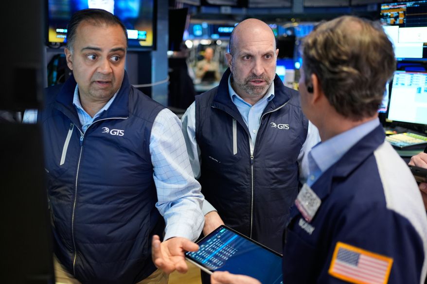 James Denaro, center, and Dilip Patel, left, work on the floor at the New York Stock Exchange in New York, Wednesday, March 25, 2026. (AP Photo/Seth Wenig)