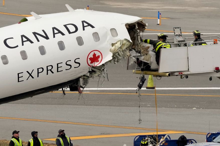 Airport firefighters remove loose debris from the wreckage of an Air Canada Express jet, Wednesday, March 25, 2026, just off the runway where it had collided with a Port Authority fire truck Sunday night at LaGuardia Airport in New York. (AP Photo/Yuki Iwamura)