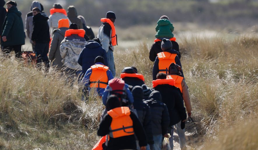 Migrants trying to reach Britain, walk on a beach shore in Gravelines, northern France, Wednesday, March 18, 2026. (AP Photo/Jean-Francois Badias)