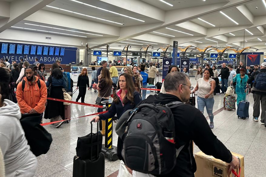 Travelers stand in a TSA checkpoint line at Hartsfield–Jackson Atlanta International Airport on Friday, March 27, 2026. (AP Photo/Emilie Megnien)