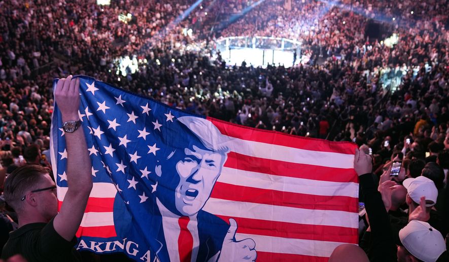 People hold a flag as President-elect Donald Trump arrives at UFC 309 at Madison Square Garden, Nov. 16, 2024, in New York. (AP Photo/Evan Vucci, File)