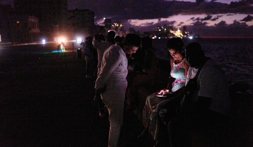 People spend the night in the dark on the Malecon during a blackout in Havana, Cuba, Saturday, March 21, 2026. (AP Photo/Ramon Espinosa)