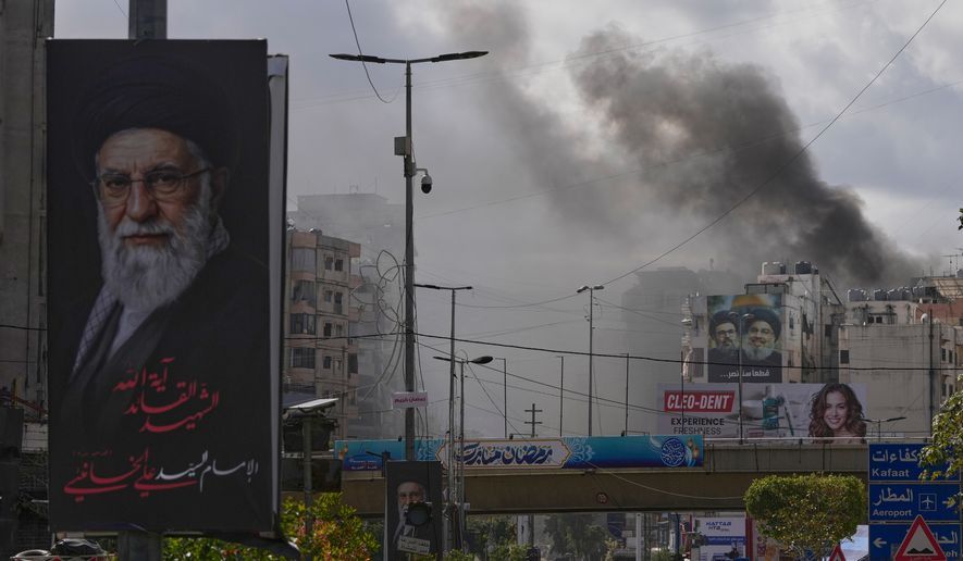 A portrait of Iran's late Supreme Leader Ayatollah Ali Khamenei, left, is seen, as smoke rises following an Israeli airstrike in Dahiyeh, Beirut's southern suburbs, Lebanon, Monday, March 30, 2026. (AP Photo/Hassan Ammar)