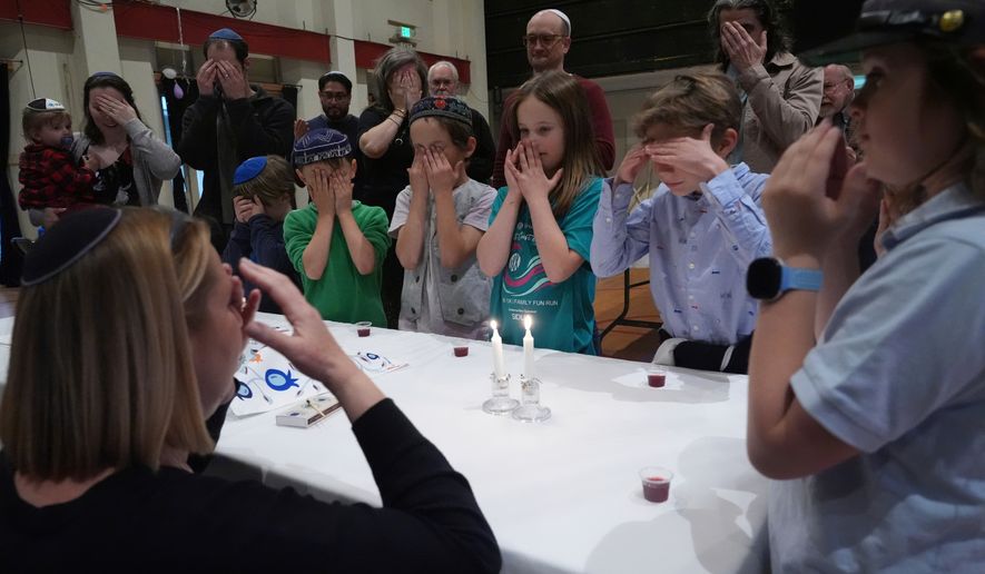 FILE - Cantor Ruth Berman Harris, left, who leads the congregation in lieu of a full-time rabbi, lights candles to celebrate Seder with congregants of the 104-year-old Pasadena Jewish Temple and Center which burned down in the Jan. 2025 Eaton fire, gathered for a Passover at the First United Methodist Church in Pasadena, Calif. on Friday, April 4, 2025. (AP Photo/Damian Dovarganes, File)