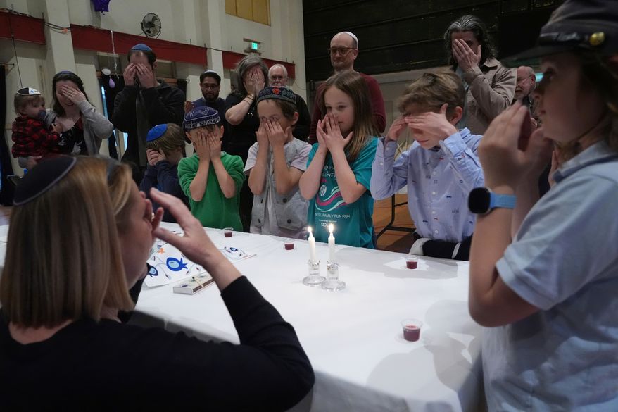 FILE - Cantor Ruth Berman Harris, left, who leads the congregation in lieu of a full-time rabbi, lights candles to celebrate Seder with congregants of the 104-year-old Pasadena Jewish Temple and Center which burned down in the Jan. 2025 Eaton fire, gathered for a Passover at the First United Methodist Church in Pasadena, Calif. on Friday, April 4, 2025. (AP Photo/Damian Dovarganes, File)