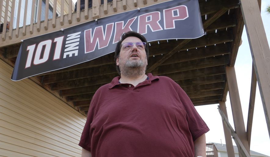 D.P. McIntire stands beneath a WKRP banner in the backyard of his home in Raleigh, N.C., on Thursday, April 2, 2026. (AP Photo/Allen G. Breed)